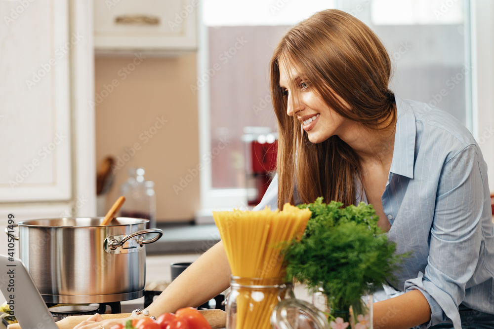 Young beautigul woman cooking in her kitchen