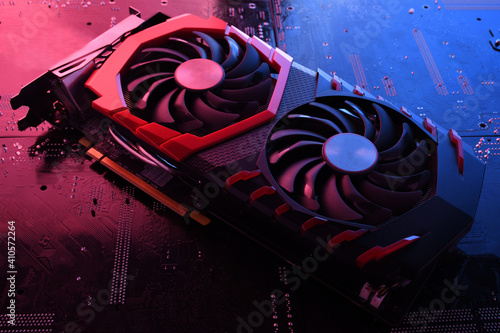 Computer game graphics card, videocard with two coolers on circuit board ,motherboard background. Close-up. With red-blue lighting
