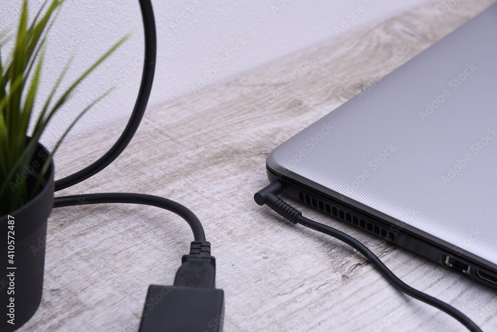 Laptop, computer is charging from a 220-volt outlet on a desk near the wall. Energy, accumulation. Mockup Laptop, computer is charging from a 220-volt outlet on a desk near the wall. Energy, accumulation. Mockup
