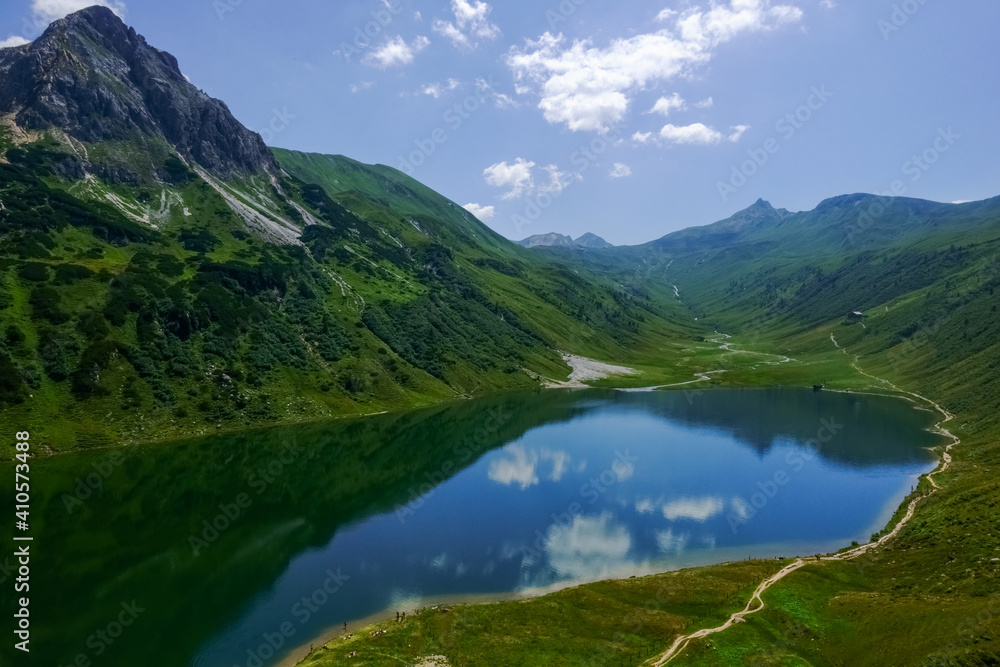 hiking trail on a deep blue mountain lake in a green landscape in the summer hiking trail on a deep blue mountain lake in a green landscape in the summer
