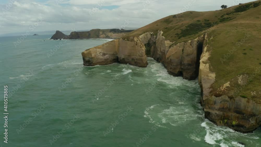 Orbiting aerial shot of cliffs along the coastline in New Zealand during the day Orbiting aerial shot of cliffs along the coastline in New Zealand during the day