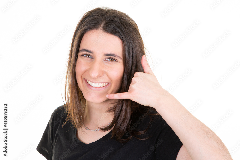 Young woman smiling making phone gesture with hand and fingers like talking on phone in communication concept Young woman smiling making phone gesture with hand and fingers like talking on phone in communication concept