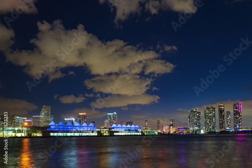 Miami night downtown, city Florida. Miami city skyline panorama with urban skyscrapers over sea with reflection.