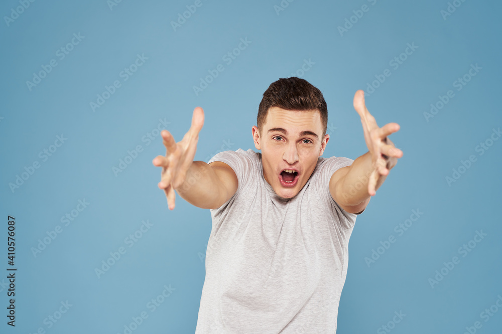 cheerful man in a white t-shirt gesturing with his hands emotions blue background cheerful man in a white t-shirt gesturing with his hands emotions blue background