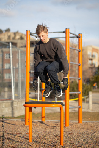 Teenager doing box jumping (box jumps) outdoors during pandemic on playground.
