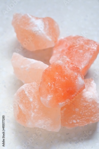 Pink himalayan salt pieces close-up on a light marble background.Pink crystal salt