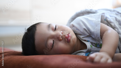 Close up view of baby boy sleeping on comfortable bed at home.