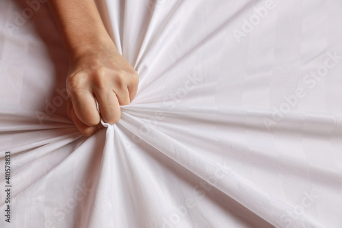 Billede på lærred Close up young sexy woman hands pulling white sheets in ecstasy in hotel