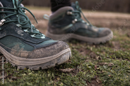 Women's trekking dirty boots in the grass and mud