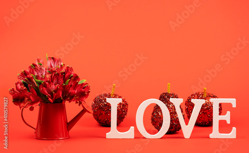 Red alstroemerias in a watering can on a red background. Greeting card. photo