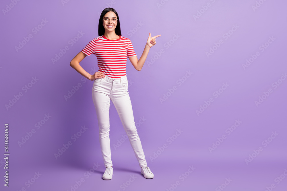 Full size photo of beautiful happy young woman point empty space advert wear white pants isolated on purple color background Full size photo of beautiful happy young woman point empty space advert wear white pants isolated on purple color background