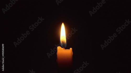 Close-up of a woman's hands lighting a candle with a match in the dark, it burns and after a while a gust of wind extinguishes it.