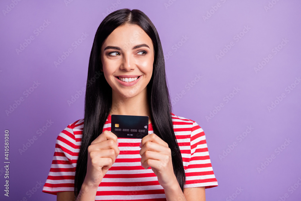Photo of happy cheerful young woman hold debit card look empty space spend money isolated on violet color background Photo of happy cheerful young woman hold debit card look empty space spend money isolated on violet color background