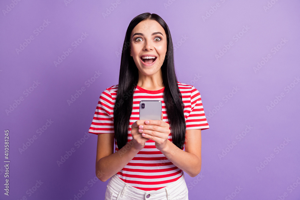 Portrait of amazed shocked woman wear red striped t-shirt like reaction isolated on purple color background