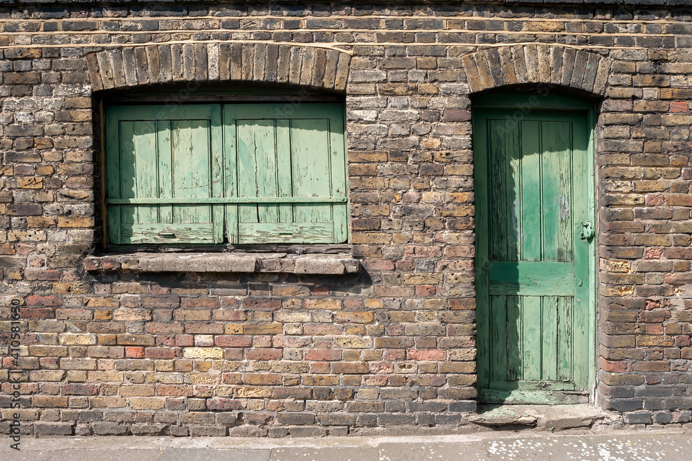 Obraz premium Old Green wooden door and window with wooden shutters on victorian building