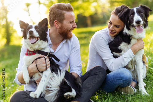 Canvas Print Happy young couple walking, playing with dogs in a park