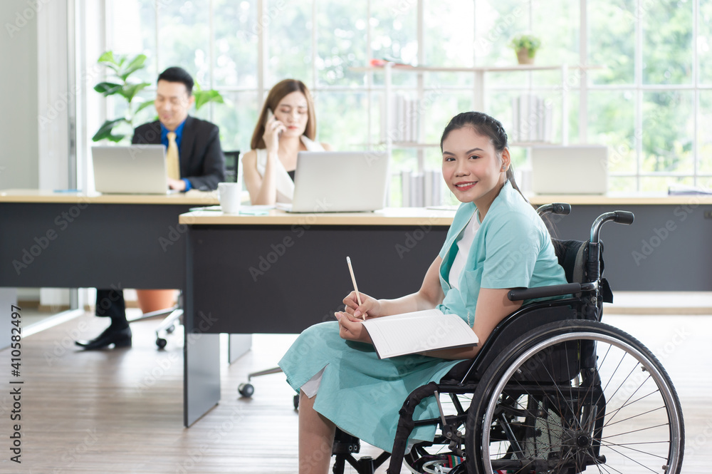 Smiling young Asian woman office worker in wheelchair holding pencil look at camera, disabled people working with colleague at workplace Smiling young Asian woman office worker in wheelchair holding pencil look at camera, disabled people working with colleague at workplace