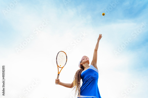 Tennis ball serving. Correct stance and practiced movements are essential for a good shot. A talented tennis player woman has been performing a well-trained movement for years. Ball up to the sky