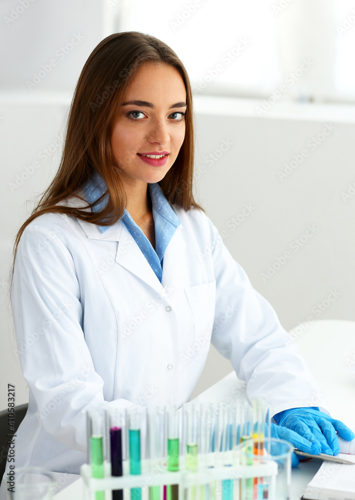 Smiling beautiful technician woman portrait and sample bottle with poison fluid. Medical worker in uniform use reagent tube for virus infection exam or biological toxic reaction, drug creation Smiling beautiful technician woman portrait and sample bottle with poison fluid. Medical worker in uniform use reagent tube for virus infection exam or biological toxic reaction, drug creation