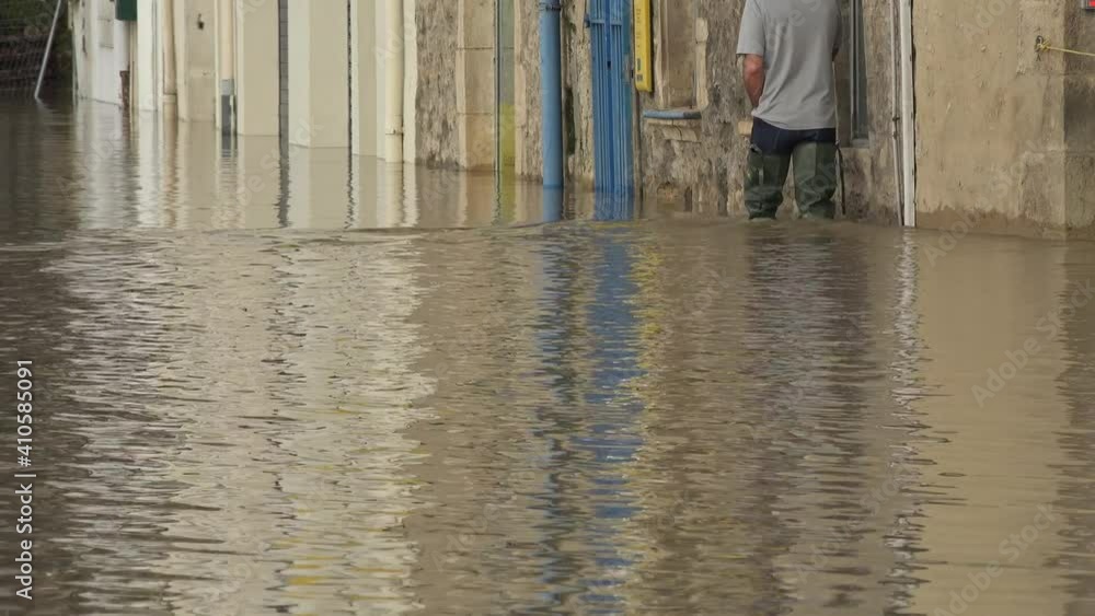 France, La Reole, February 4, 2021, The River Garonne overflowed its banks following heavy rainfall, fA man equipped with waders reaches his flooded house. High quality 4k footage France, La Reole, February 4, 2021, The River Garonne overflowed its banks following heavy rainfall, fA man equipped with waders reaches his flooded house. High quality 4k footage