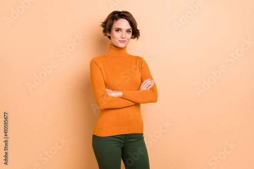 Canvas Print Photo of adorable serious young girl orange turtleneck arms crossed isolated bei