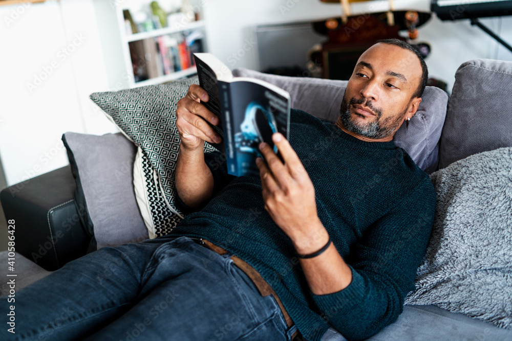 40 years old man relaxing on the couch and reading a book 40 years old man relaxing on the couch and reading a book