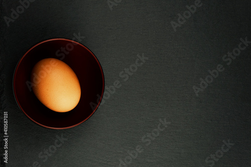 A Single Egg with Condensation on it's shell, presented in a Japanese Bowl on a Slate Background. 