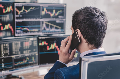 Tableau sur toile Over the shoulder view of and stock broker trading online while accepting orders by phone
