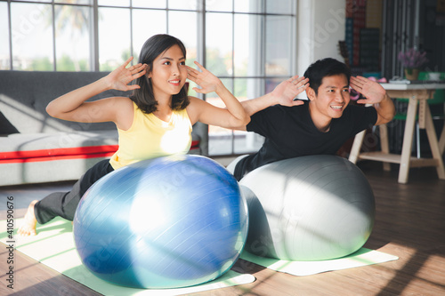 Couple of Asian boy and Asian young girl practicing yoga with exercise balls in living room at home, Healthy indoor sports activity