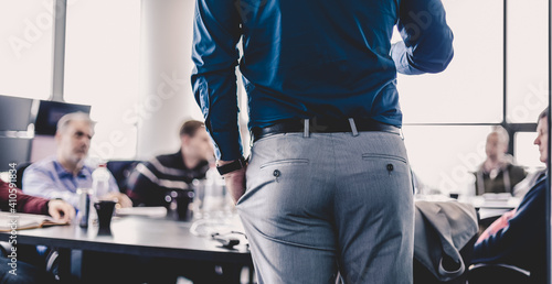 Businessman making a presentation at office. Business executive delivering a presentation to his colleagues during meeting or in-house business training. Rear view. Business and entrepreneurship.