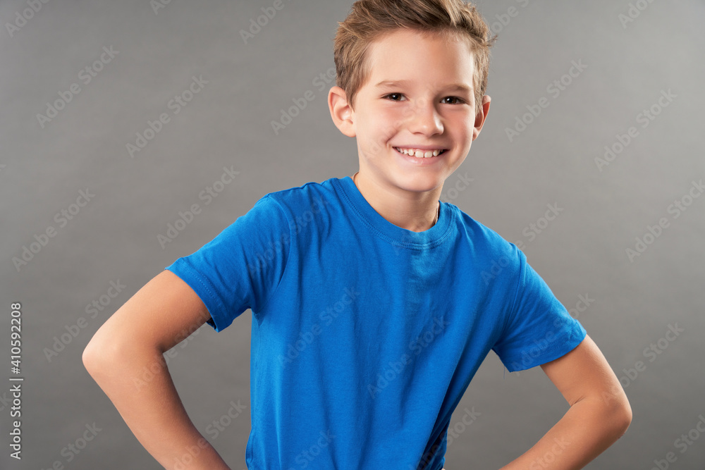 Cute cheerful boy standing against gray background Cute cheerful boy standing against gray background