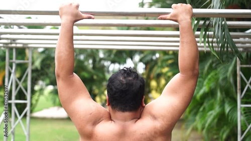 Slow motion of strong muscle man jump and hold the bar outdoor in sport.