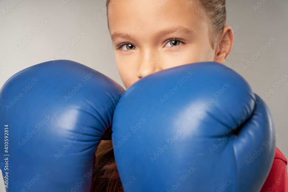 Adorable girl in boxing gloves standing against gray background Adorable girl in boxing gloves standing against gray background