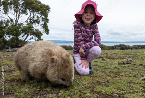 фотографія Closeup of a caucasian girl with a pink hat, next to a wombat outdoors