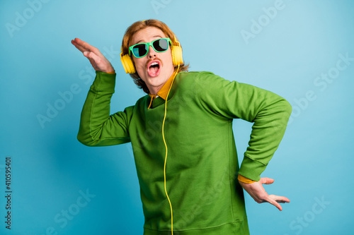 Photo of young handsome funky funny playful man in headphones fooling around isolated on blue color background