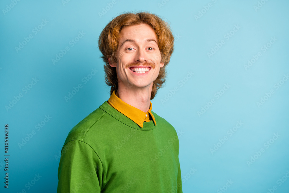 Photo of young handsome cute funky funny smiling positive man with wavy hair and mustache isolated on blue color background Photo of young handsome cute funky funny smiling positive man with wavy hair and mustache isolated on blue color background