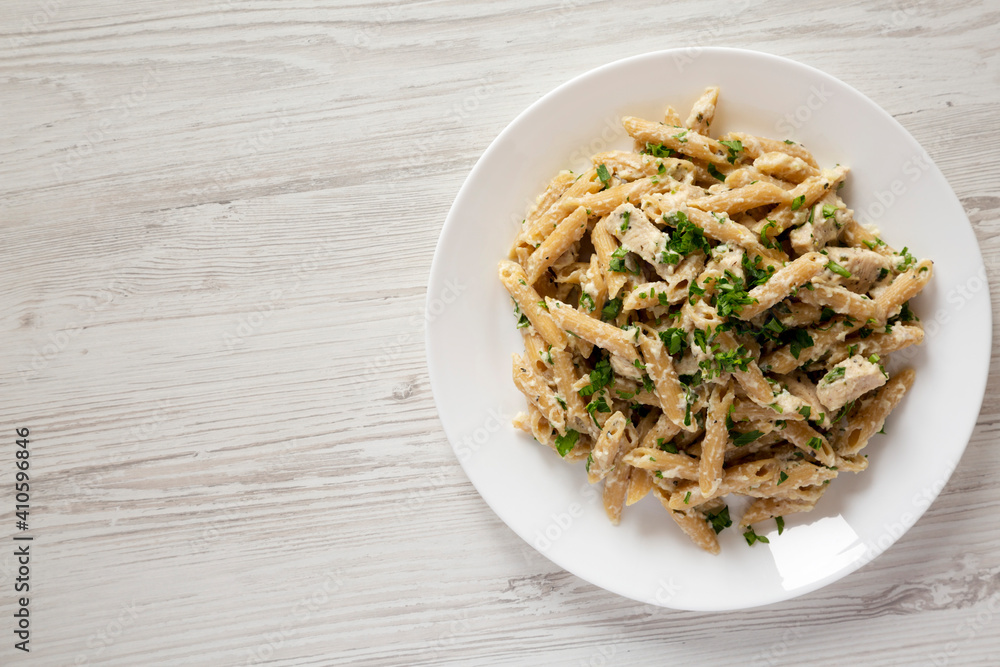 Homemade Chicken Alfredo Penne with Parsley on a white wooden background, top view. Overhead, from above, flat lay. Copy space. Homemade Chicken Alfredo Penne with Parsley on a white wooden background, top view. Overhead, from above, flat lay. Copy space.