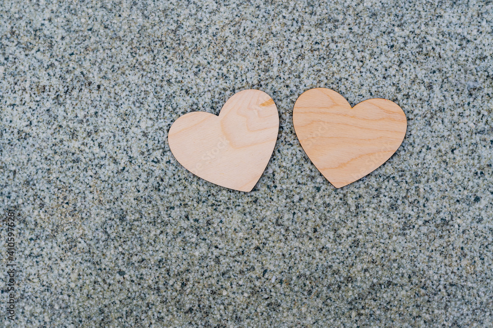 Fototapeta premium Two light wooden hearts lie on a granite surface, a sign of love and fidelity, valentine's day 