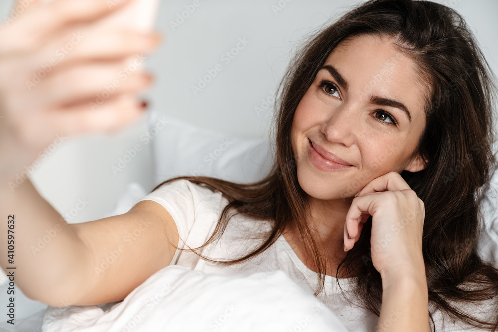 Happy nice girl smiling while taking selfie on mobile phone Happy nice girl smiling while taking selfie on mobile phone
