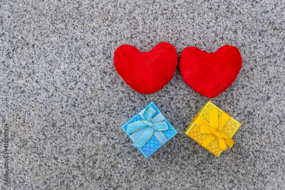 Two red hearts stand and two colored gift boxes lie on brown granite slab, valentine's day Two red hearts stand and two colored gift boxes lie on brown granite slab, valentine's day