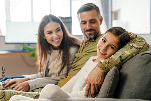 Photography Happy masculine military man hugging his family while sitting on sofa