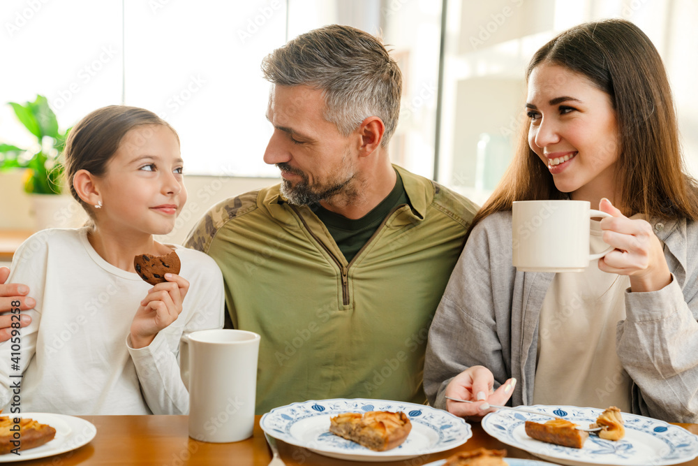 Happy masculine military man hugging his family while having breakfast Happy masculine military man hugging his family while having breakfast