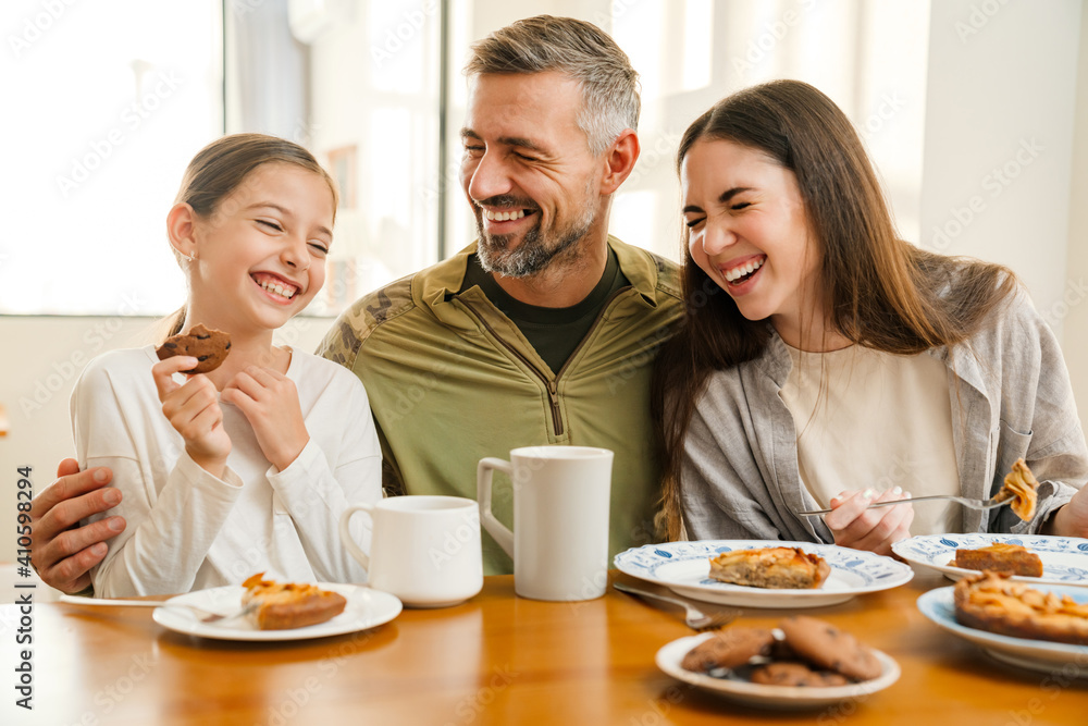 Joyful masculine military man hugging his family while having breakfast Joyful masculine military man hugging his family while having breakfast