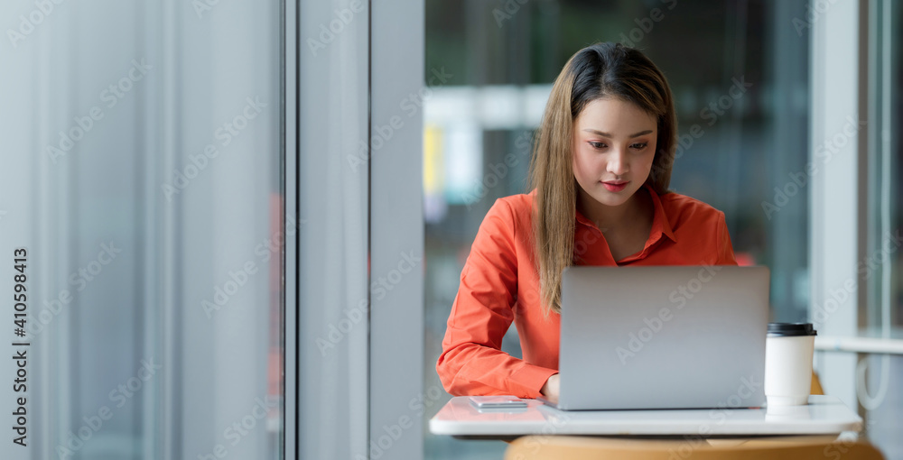 Fototapeta premium Beautiful young woman using laptop sitting on a coffee shop