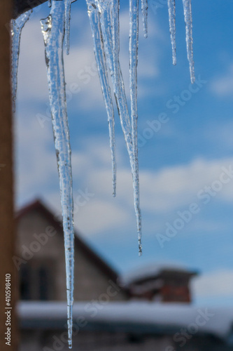 Long and dangerous icicles hanging from roof of house. Winter season concept. Frost and snow weather