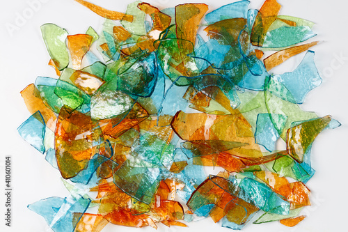 Background of broken fragments of colored multicolored glass with blurred reflections on white background .