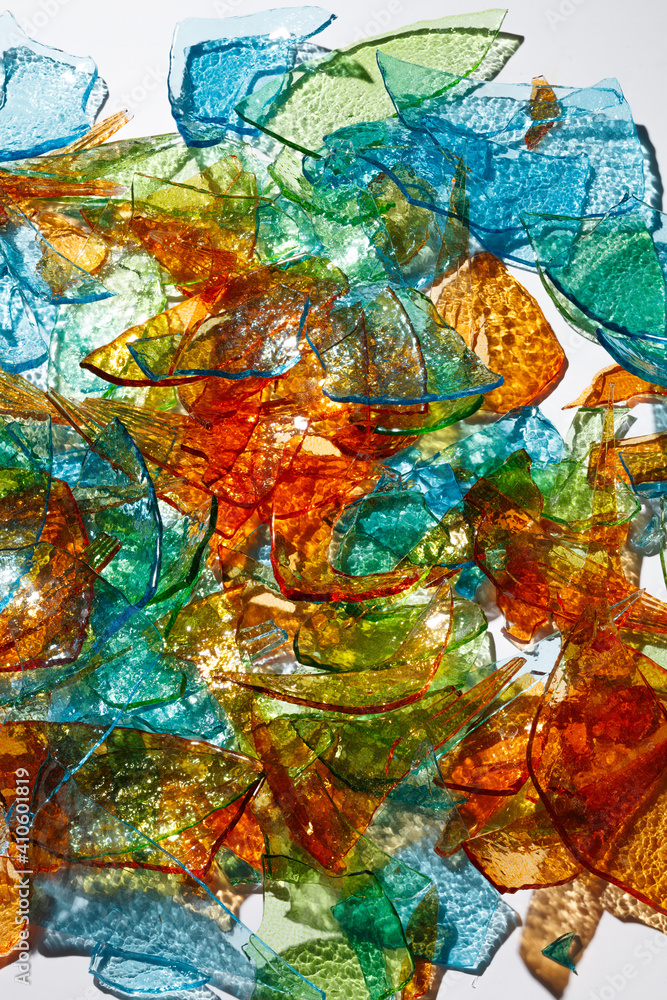 Mosaic of Broken Glass. Background of fragments of colored multicolored glass with blurred reflections on white background .Selective focus