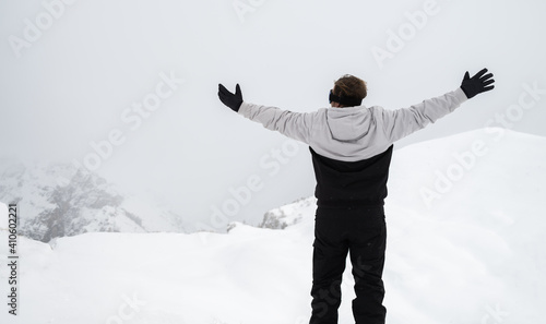 A man stands on a ridge with his arms outstretched in winter