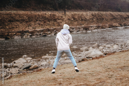 girl jumping with happiness near a mountain river