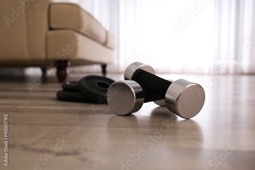 Dumbbells and weight plates on floor in room. Home fitness